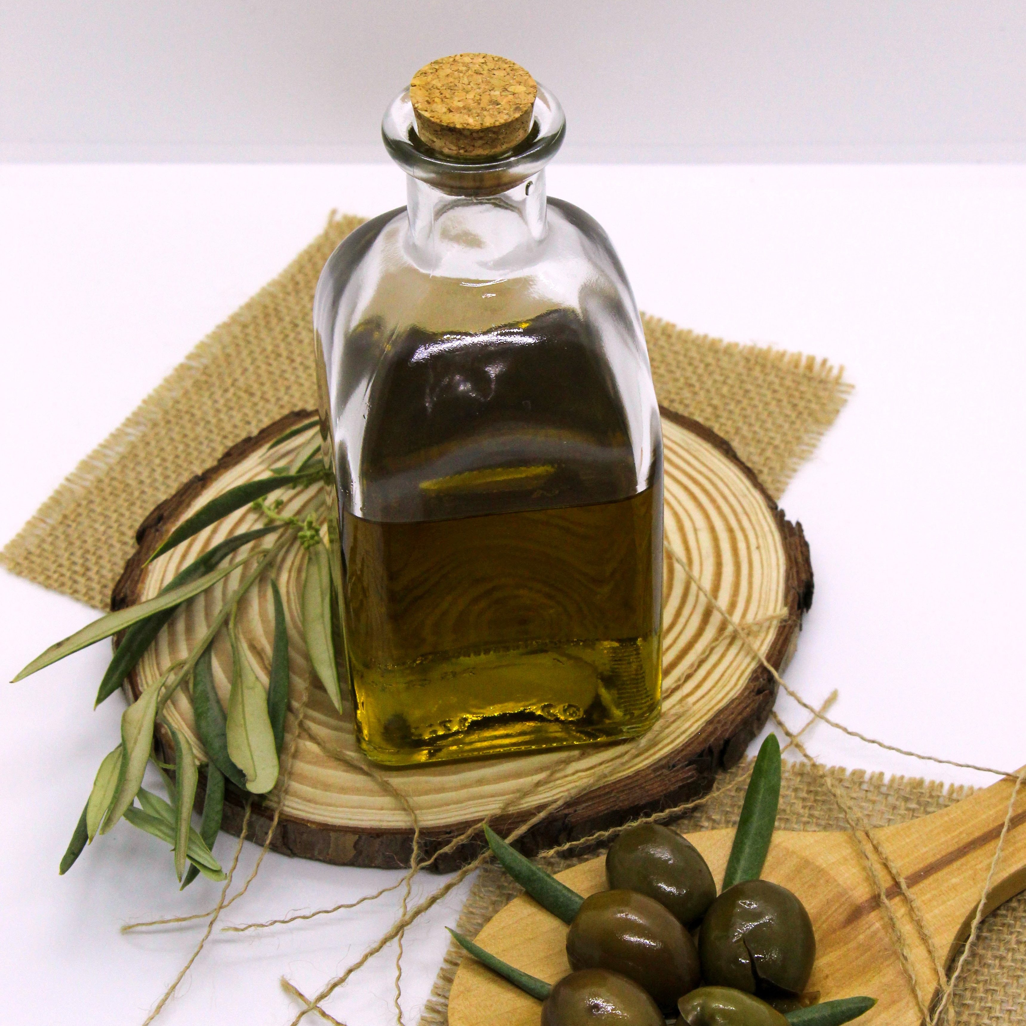 A bottle of olive oil and a wooden spoon of green olives