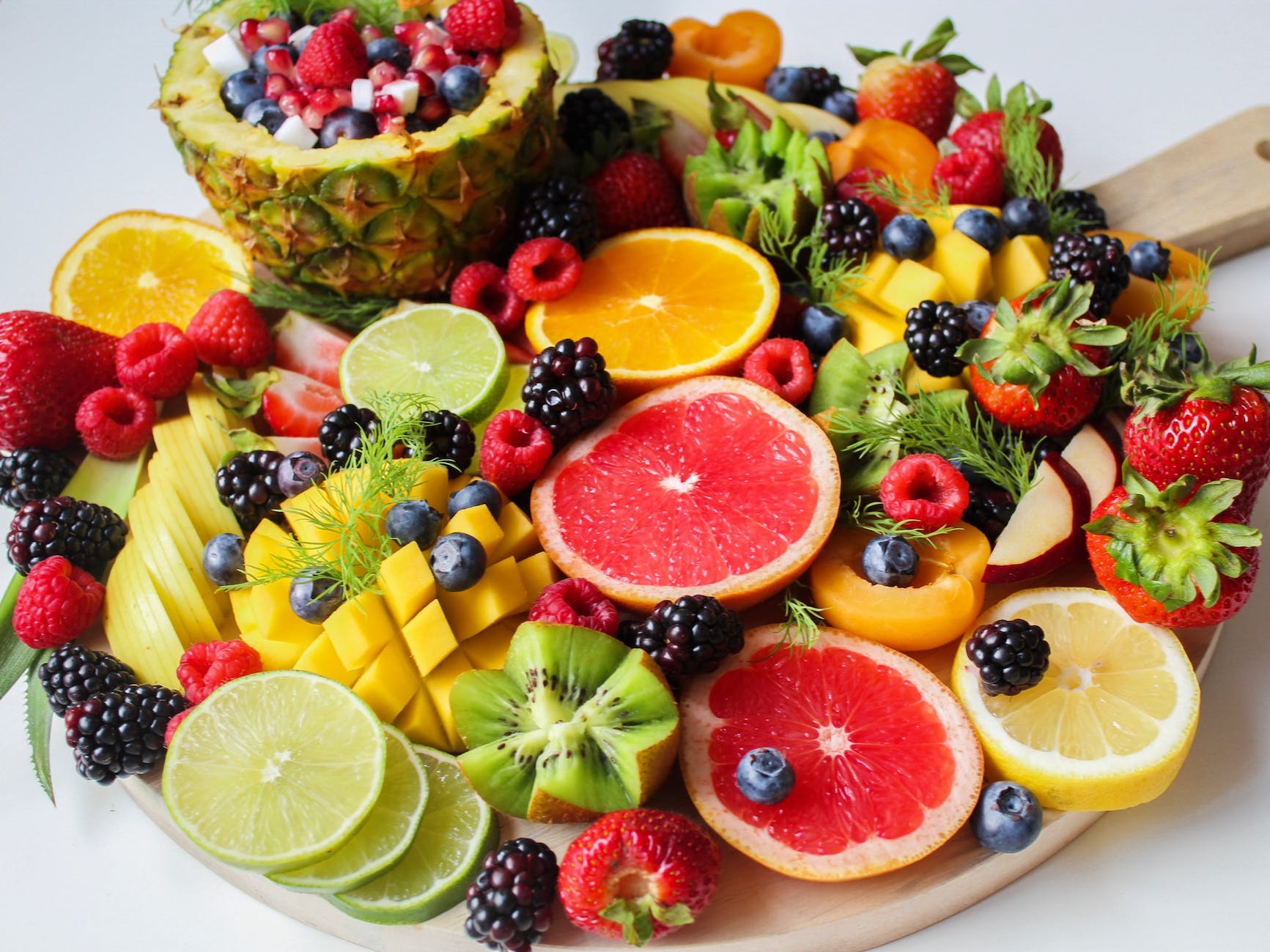 A platter of healthy fruits: grapefruit, kiwi, blackberries, melon, raspberries, blueberries